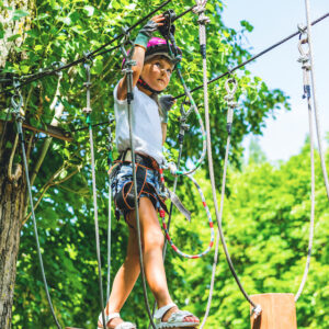 Happy 5 Year Old Girl In Pink Protective Helmet And Equipment In A Rope Park In Summer.